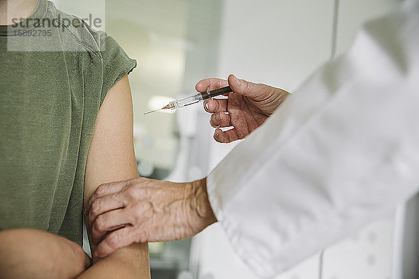 Arzt injiziert Impfstoff in den Arm eines Teenagers