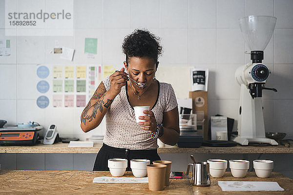 Frau arbeitet in einer Kaffeerösterei und verkostet ein Produkt