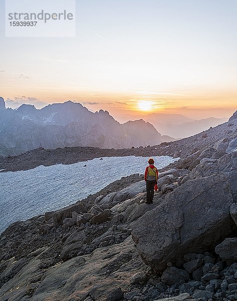 Wanderin steht in felsigem alpinen Gelände und betrachtet Sonnenuntergang über Gosaukamm mit Berggipfel Bischofsmütze  Abendstimmung  Salzkammergut  Oberösterreich  Österreich  Europa
