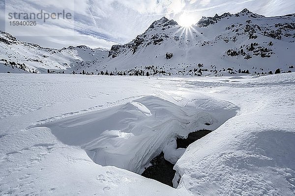 Sonne scheint über schneebedeckte Berggipfel  Klammspitzen und Tarntaler Köpfe  vorne offene Schneedecke mit darunter fließendem Bach  Wattentaler Lizum  Tuxer Alpen  Tirol  Österreich  Europa