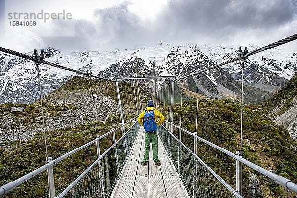 Wanderer steht auf Hängebrücke über Hooker River  Hooker Valley  Mount Cook Nationalpark  Canterbury  Neuseeland  Ozeanien