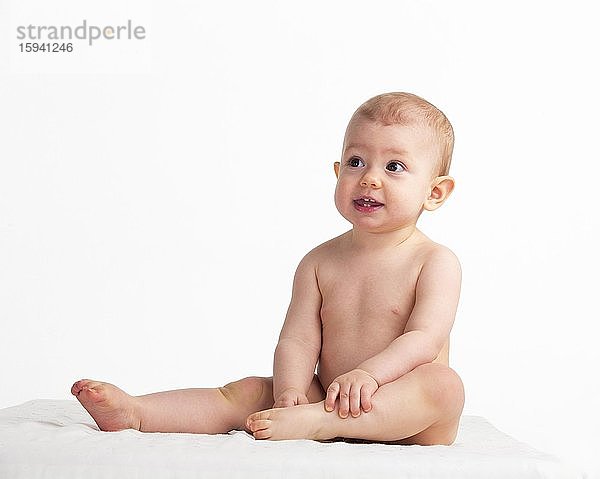 Kleines Mädchen  Baby sitzt nackt auf einer weißen Decke  1 Jahr  Österreich  Europa