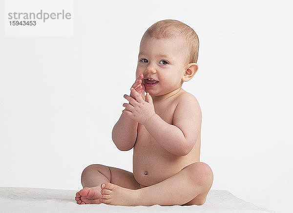 Kleines Mädchen  Baby sitzt nackt auf einer weißen Decke  1 Jahr  Österreich  Europa