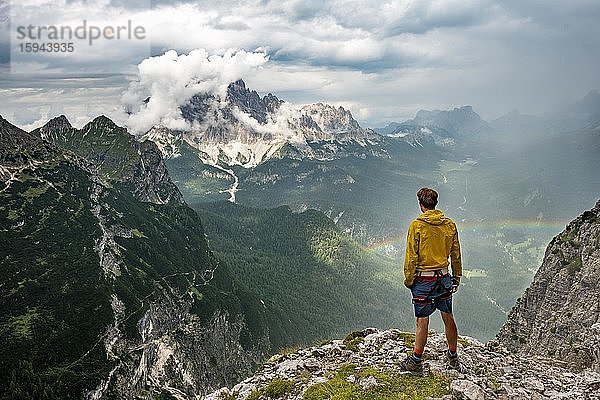 Junger Mann  hinten Berggipfel Monte Cristallo mit Regenbogen  Wanderer in den Bergen  Klettersteig Via Ferrata Vandelli  Sorapiss Umrundung  Dolomiten  Belluno  Italien  Europa