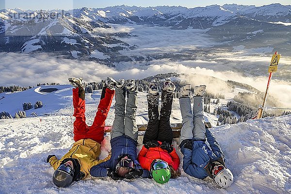 Skifahrer liegen im Schnee und strecken Beine in die Luft  schneebedeckte Berge  Sessellift im Skigebiet SkiWelt Wilder Kaiser Brixental  Brixen im Thale  Tirol  Österreich  Europa