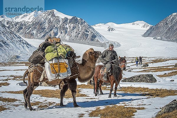 Mongolischer Hirte auf Pferd mit Trampeltier mit Gepäck führt zwei Touristen in das mongolische Altaigebirge  Provinz Bayan-Ulgii  Mongolei  Asien