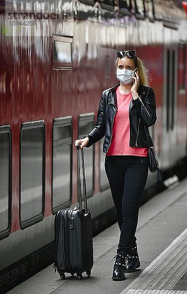 Frau mit Mundschutzmaske  wartet auf Zug  telefoniert mit Handy  Corona-Krise  Hauptbahnhof  Stuttgart  Baden-Württemberg  Deutschland  Europa