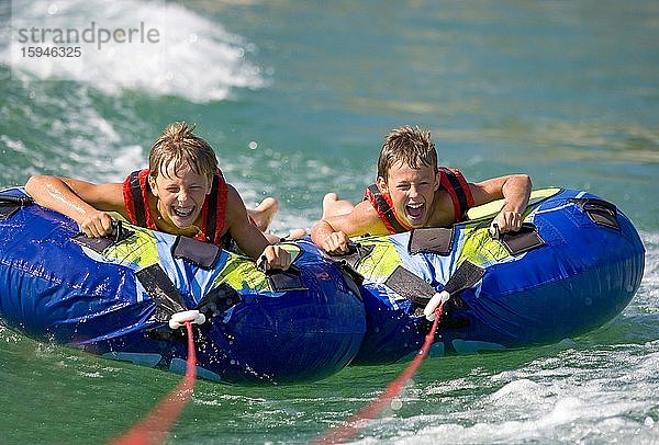 Zwei Kinder  Jugendliche raften mit Wasserreifen im See  Mondsee  Oberösterreich  Österreich  Europa