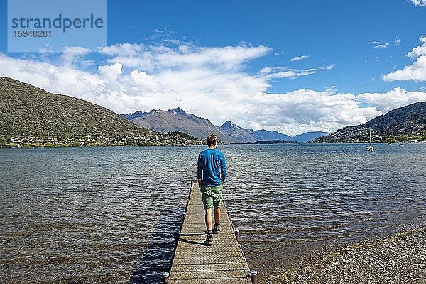 Junger Mann auf einem Steg am Lake Wakatipu  Queenstown  Otago  Südinsel  Neuseeland  Ozeanien