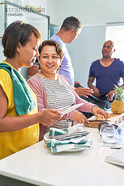 Reife Freunde sprechen und kochen in der Küche