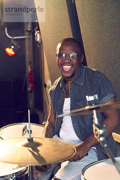 Portrait glücklicher männlicher Trommler beim Üben am Schlagzeug