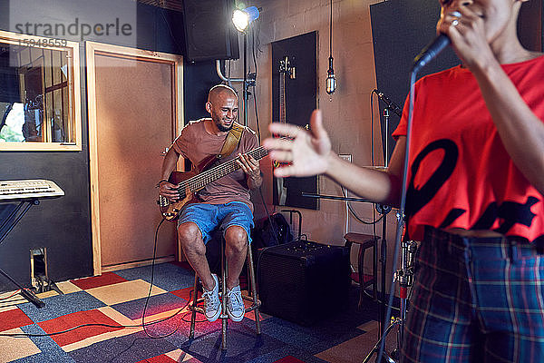 Musiker  die im Aufnahmestudio singen und Gitarre spielen