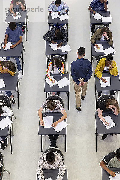 Lehrer beaufsichtigt Gymnasiasten  die am Schreibtisch Prüfungen ablegen