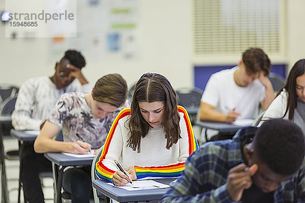 Fokussierte Gymnasiastin nimmt Prüfung am Schreibtisch am Computer ab