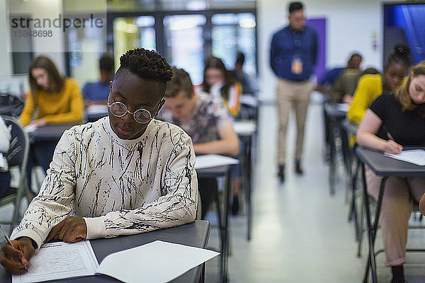 Fokussierter High-School-Schüler nimmt Prüfung am Schreibtisch ab