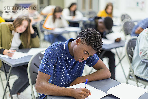 Fokussierter High-School-Schüler nimmt Prüfung am Schreibtisch im Klassenzimmer ab