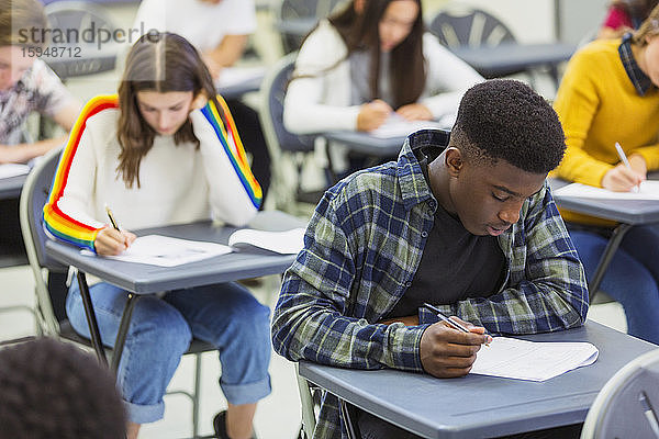 Fokussierter High-School-Schüler nimmt Prüfung am Schreibtisch im Klassenzimmer ab