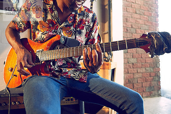 Männlicher Musiker spielt E-Gitarre in Garage