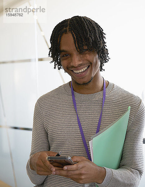 Porträt eines glücklichen Geschäftsmannes  der im Büro mit einem Smartphone simst