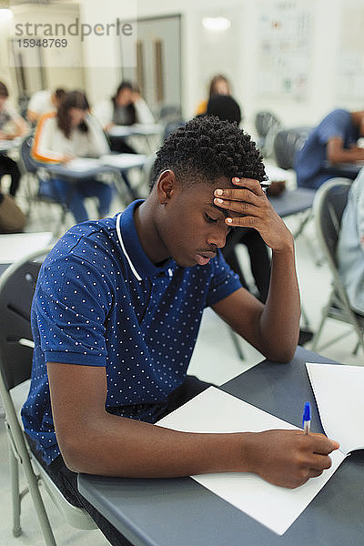 Fokussierter High-School-Schüler nimmt Prüfung am Schreibtisch im Klassenzimmer ab