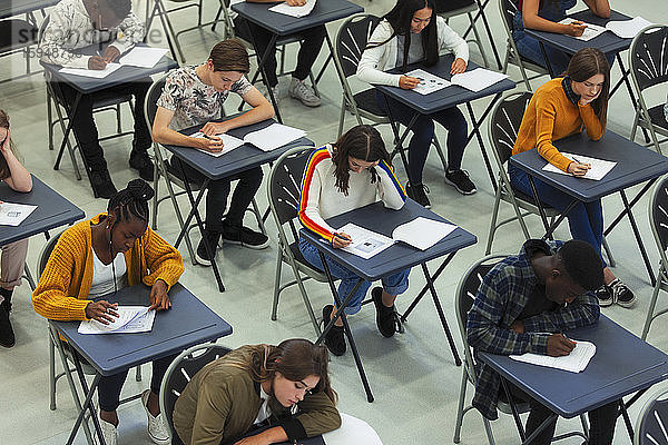 Fokussierte Gymnasiasten  die an Schreibtischen im Klassenzimmer Prüfungen ablegen