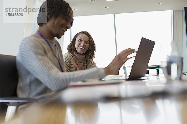 Lächelnde Geschäftsleute mit Laptop in Konferenzraumbesprechung