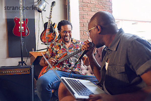 Glückliche männliche Musiker üben im Aufnahmestudio