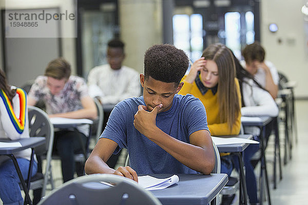 Fokussierter High-School-Schüler nimmt Prüfung am Schreibtisch im Klassenzimmer ab