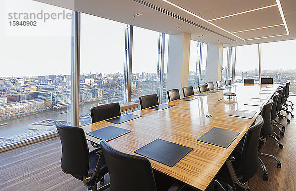 Langer Konferenztisch in modernem Hochhausbüro mit Blick auf die Stadt