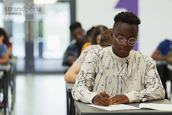 Fokussierter High-School-Schüler nimmt Prüfung am Schreibtisch im Klassenzimmer ab