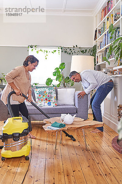Reifes Ehepaar beim Staubsaugen und Reinigen des Wohnzimmers