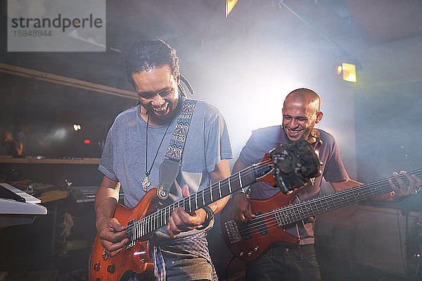 Glückliche männliche Musiker spielen E-Gitarre im Aufnahmestudio