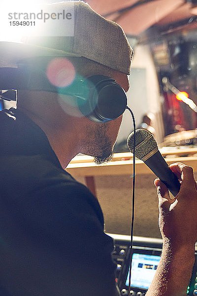 Männlicher Musikproduzent mit Mikrofon im Aufnahmestudio