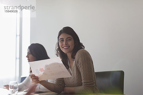 Porträt einer selbstbewussten glücklichen Geschäftsfrau mit Papierkram im Büro