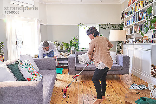 Wischen und Reinigen des Wohnzimmers eines erwachsenen Paares