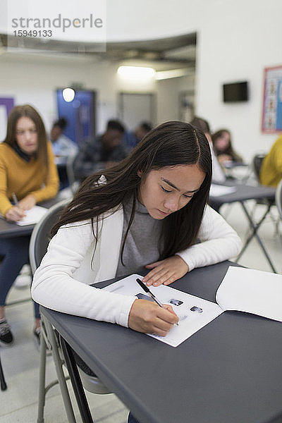 High-School-Mädchen nimmt Prüfung am Schreibtisch im Klassenzimmer ab