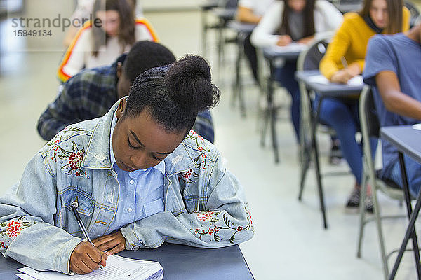 Fokussierte High-School-Schülerin nimmt Prüfung am Schreibtisch im Klassenzimmer ab