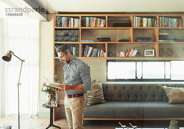 Mann liest Buch im modernen Wohnzimmer