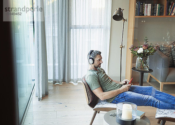 Mann entspannt sich im Wohnzimmer  hört Musik mit mp3-Player und Kopfhörern