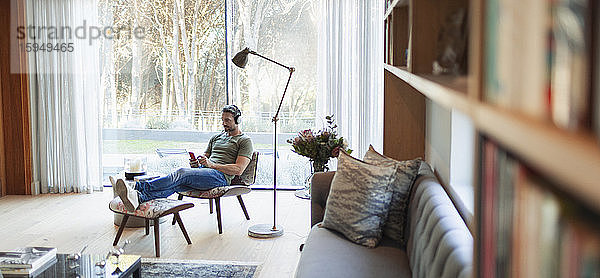 Mann entspannt sich  hört Musik mit Kopfhörern und mp3-Player im Wohnzimmer
