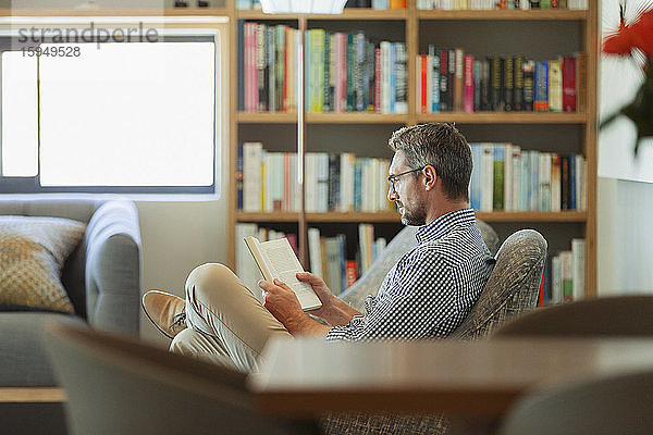 Mann entspannt sich  liest Buch im Wohnzimmer