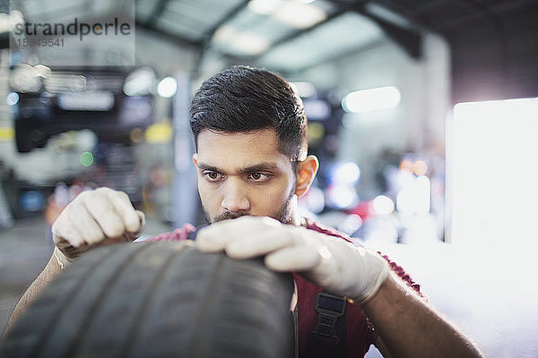 Fokussierter männlicher Mechaniker untersucht Reifen in Autowerkstatt