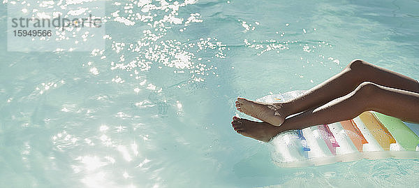 Unbeschwerte junge Frau auf einem Floß im sonnigen  ruhigen Schwimmbad