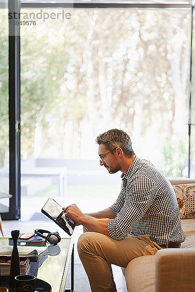 Geschäftsmann mit digitalem Tablet  der von zu Hause auf dem Sofa arbeitet