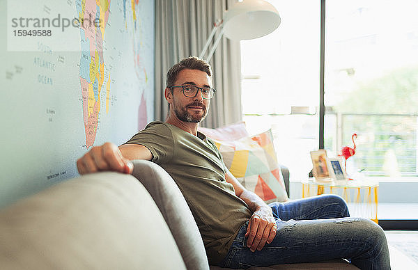 Porträt selbstbewusster Mann auf Wohnzimmer-Sofa sitzend