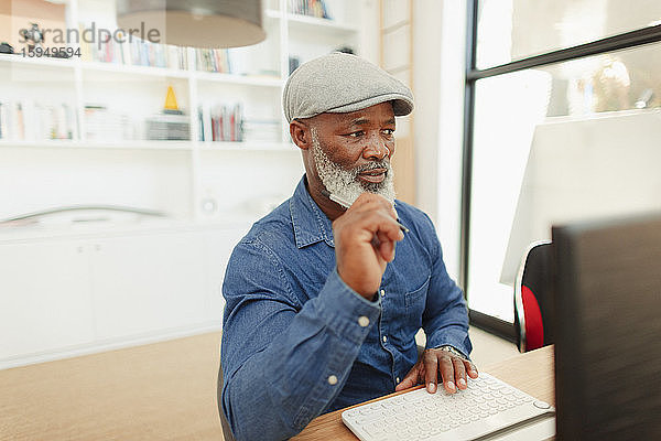 Mann am Computer  im Heimbüro arbeitend