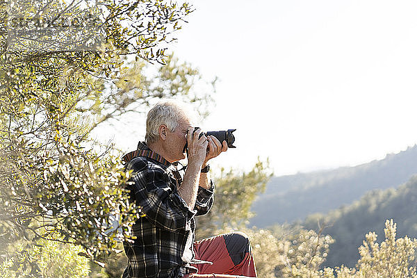 Älterer Mann beim Fotografieren in der Natur