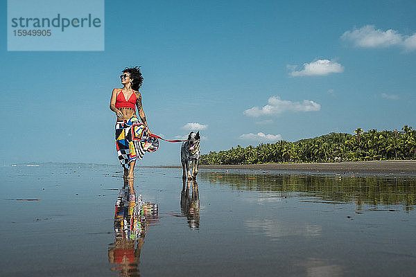 Junge Frau geht mit ihrem Hund am Strand spazieren  Costa Rica