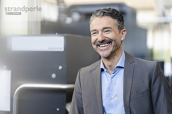 Porträt eines erfolgreichen Geschäftsmannes in der Werkstatt eines Unternehmens  lächelnd