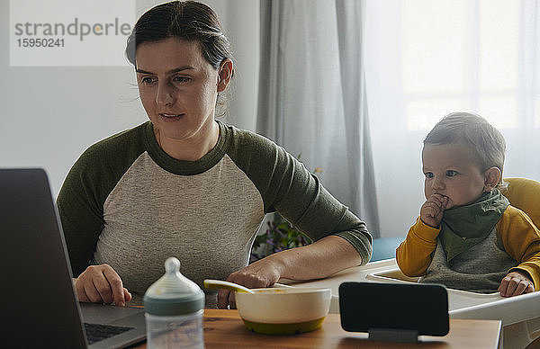 Mutter und kleiner Sohn schauen gemeinsam am Laptop zu Hause